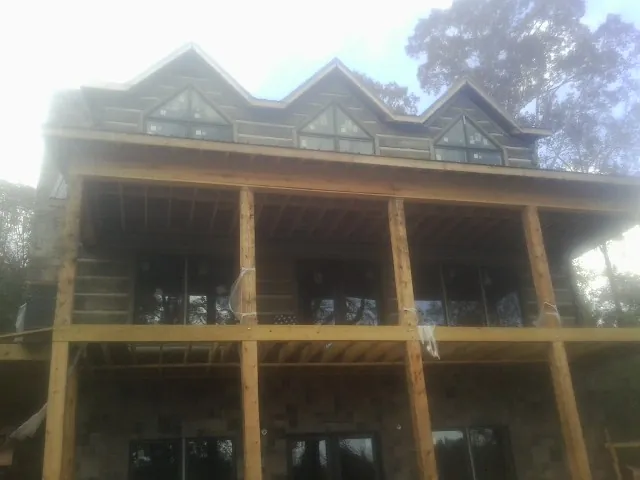 Dormers and porch framing on a large log home under construction — Roof Coating work by our crew in Nixa