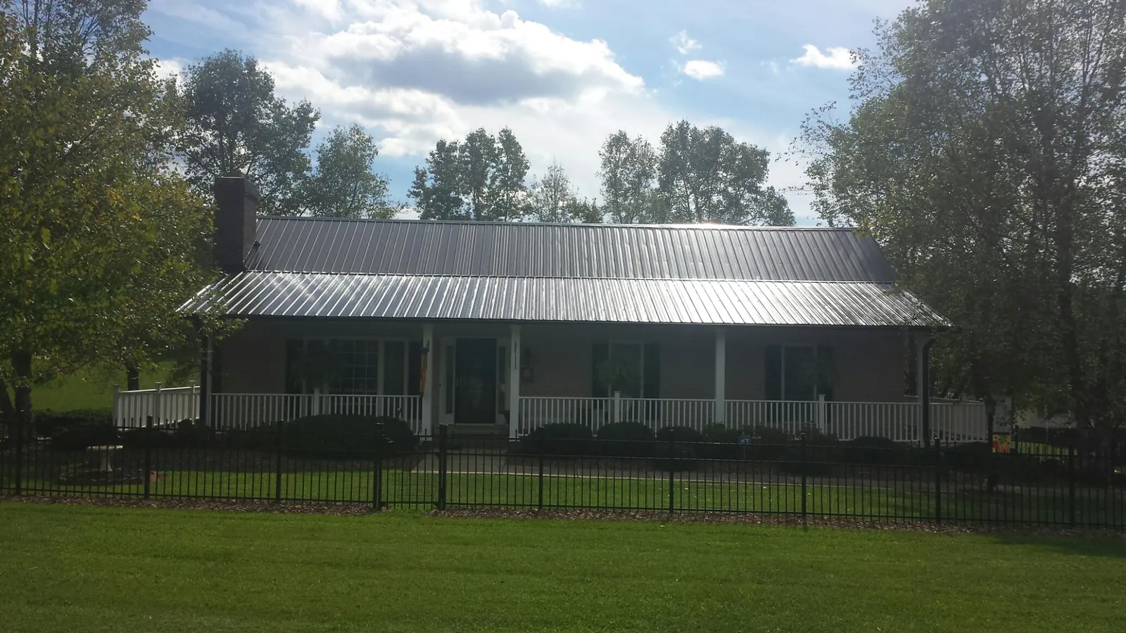 Gray metal roof on a brick ranch with a full width front porch — Gutter Guard Installation work by our crew in Nixa