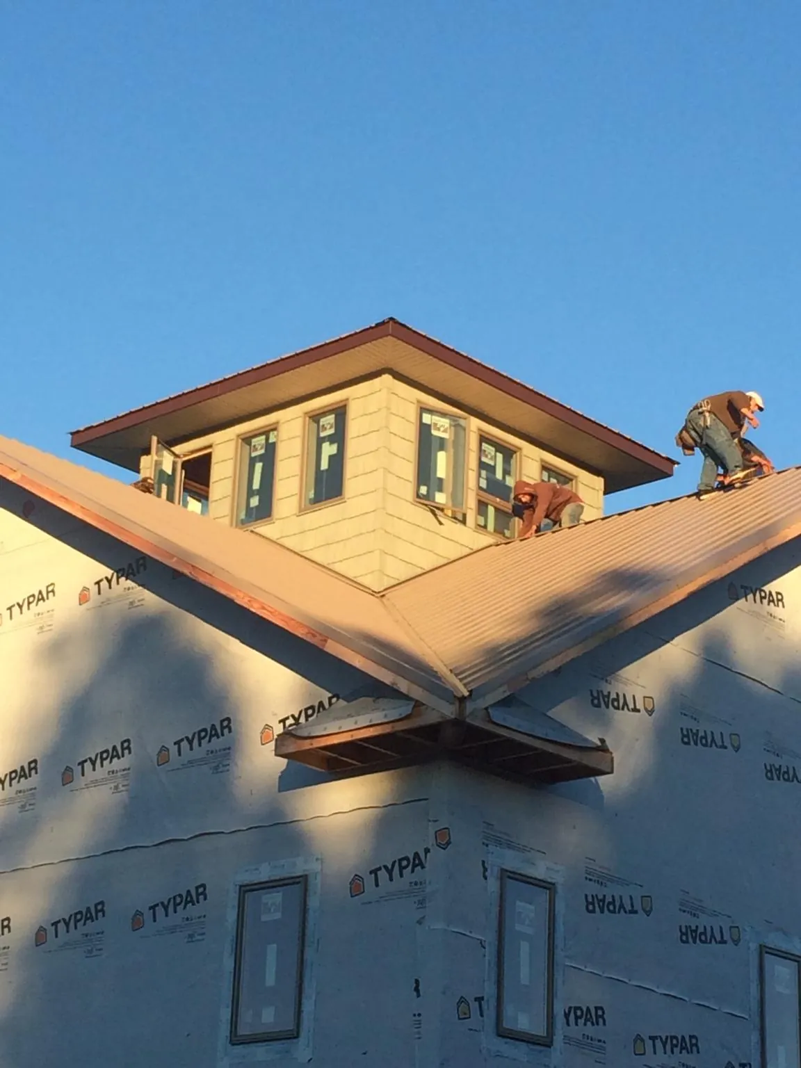 Roofers working around a rooftop cupola on a new metal roof at sunset — Roof Waterproofing in Nixa by Roofing Brothers